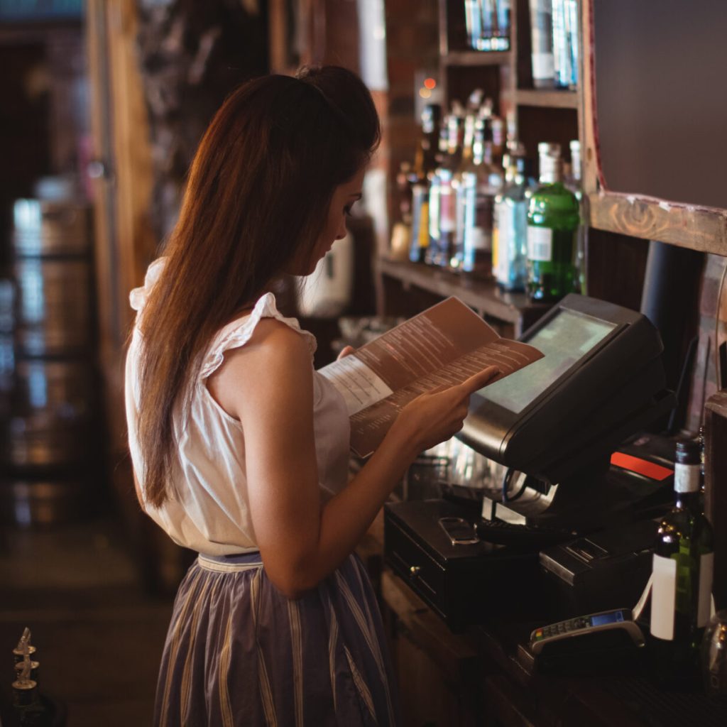 Female bar tender looking at menu in pub